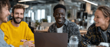 Des bénévoles réunis autour d’une table consultent un ordinateur portable pour gérer la comptabilité d’une association en toute transparence.