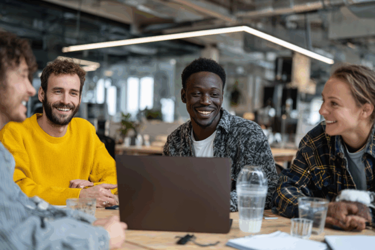 Des bénévoles réunis autour d’une table consultent un ordinateur portable pour gérer la comptabilité d’une association en toute transparence.